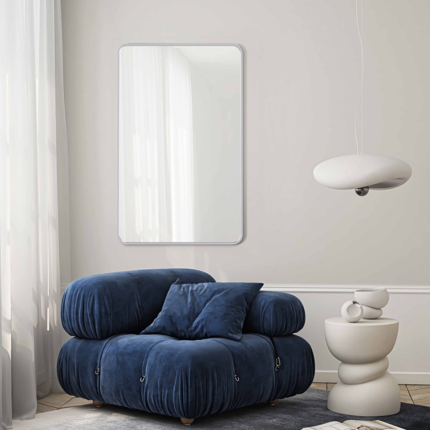 Lustro Corner Silver w srebrnej ramie w salonie nad kobaltowym fotelem